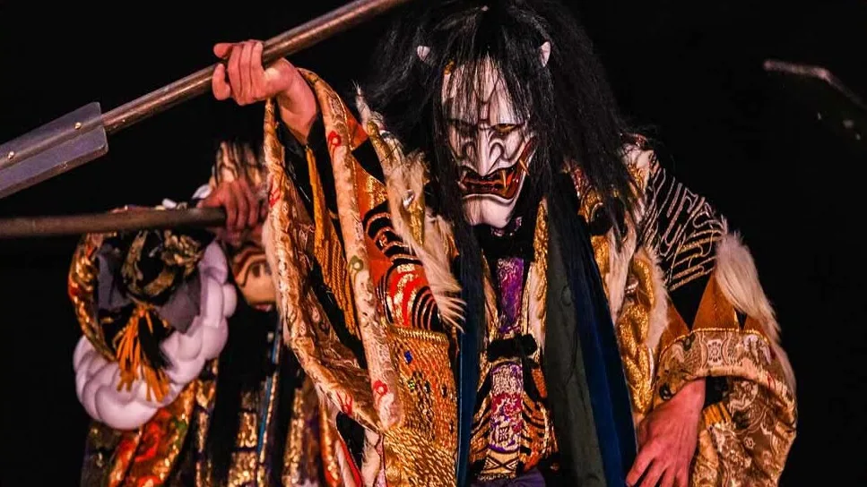 A man in Japanese theater kagura wearing a white oni mask and a traditional kimono
